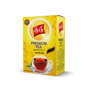 Bright yellow tea box labeled 'Her Te' (Her Tea) with a red logo, decorative swirls, and a glass cup of tea visible on the bottom right; premium loose tea.